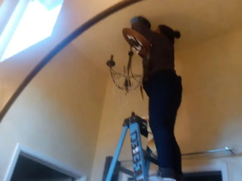 Electrician installing a chandelier in a Alamosa residence